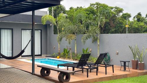 eine Terrasse mit zwei Stühlen und einem Swimmingpool in der Unterkunft Casa em Foz do Iguaçu com piscina, churrasqueira e natureza ao redor para sua família in Foz do Iguaçu