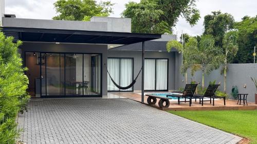 ein Haus mit einer Terrasse mit 2 Stühlen und einem Tisch in der Unterkunft Casa em Foz do Iguaçu com piscina, churrasqueira e natureza ao redor para sua família in Foz do Iguaçu