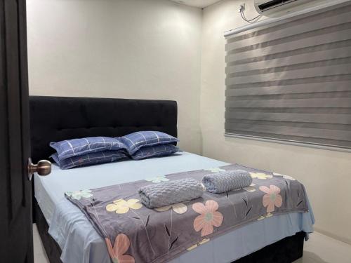 um quarto com uma cama com travesseiros e uma janela em Homestay Casa Cinta Pendang em Pendang