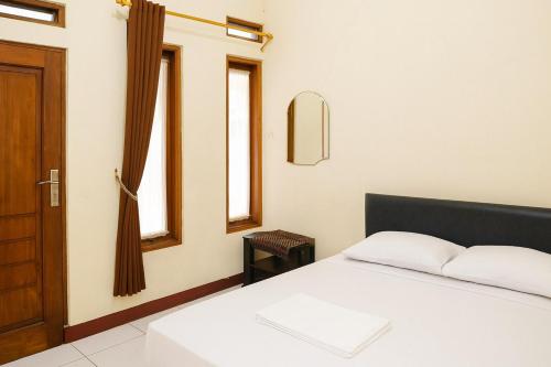 a bedroom with a bed and a door and windows at RedDoorz at Hotel Galuh Putra Pangandaran in Pangandaran