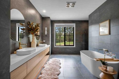 La salle de bains est pourvue de 2 lavabos, d'une baignoire et d'une fenêtre. dans l'établissement Burrugin Lodge, à Beaumont