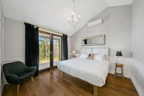 a bedroom with a bed and a chair and a window at Block Eight Estate Gum Trees Villa in Belford