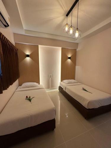 a bedroom with two beds and a chandelier at Pakchong Phubade Hotel in Pak Chong