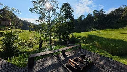 a bench sitting on a deck with a view of a field at Chibacall ชิบะคอล, Karen Mountain Hideaway Homestay in Ban Pha Mon
