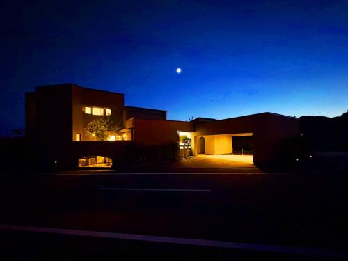 une maison la nuit avec la lune dans le ciel dans l'établissement 隠れ家アートヴィラ Villa Revolla, à Makinohara
