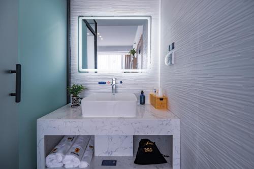 a white bathroom with a sink and a mirror at Super 8 Selected Hotel Sanya Bay Coconut Dream Corridor in Sanya