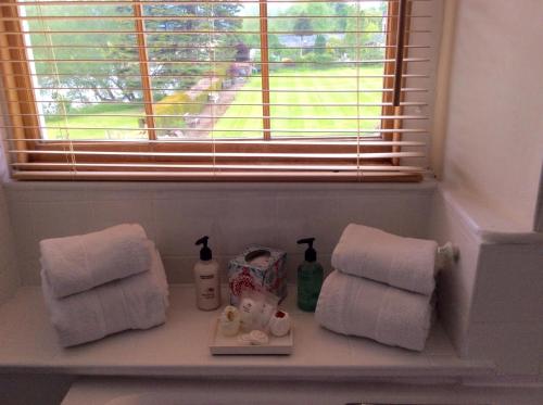 a bathroom shelf with towels and a window at Aberllynfi Riverside Guest House in Glasbury