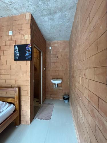 een badkamer met een wastafel en een bakstenen muur bij Time Travellers in Auroville