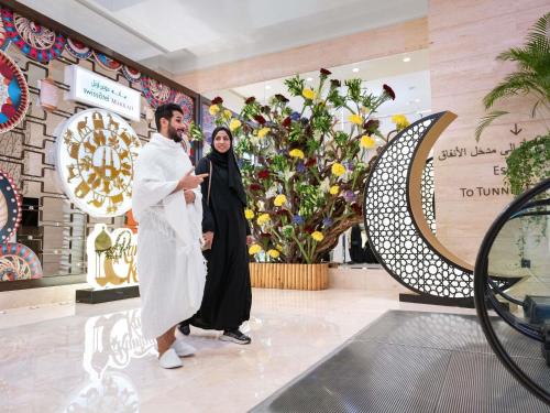 a man and a woman standing in a shopping mall at Swissotel Makkah in Makkah