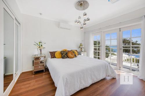 Dormitorio blanco con cama y vistas al océano en Luxury Waterfront Getaway, en Toukley