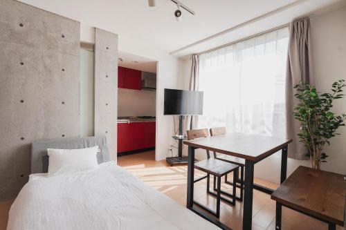 ein Schlafzimmer mit einem Bett, einem Tisch und einem Schreibtisch in der Unterkunft Ｂｒａｎｃｈｅ住吉ＥＡＳＴ in Fukuoka