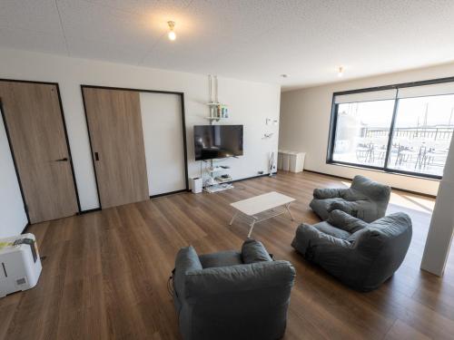 a living room with two chairs and a tv at Rockstar Villa 尾崎浜STYLE in Awaji