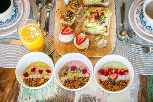 una mesa con cuatro cuencos de comida y un plato de comida en Pousada Rosa 08 - Café da manhã Gourmet, Suítes com Banheira a 150m do Centrinho da Praia do Rosa, en Praia do Rosa