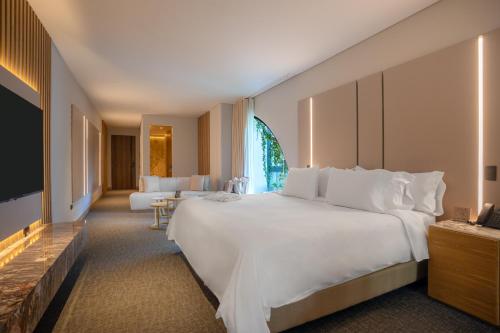 a bedroom with a large white bed and a living room at Alko Hotel Integrado in Cali