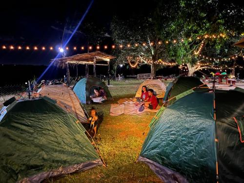 Un grupo de personas acampando en tiendas de campaña por la noche. en Thrill Playgrounds & Tipi Cafe, en Libona