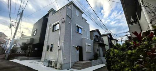 a small gray building with windows on a street at 新築江の電腰越駅前徒歩1分鎌倉江の島観光に最適鎌倉腰越駅前a棟 in Kamakura