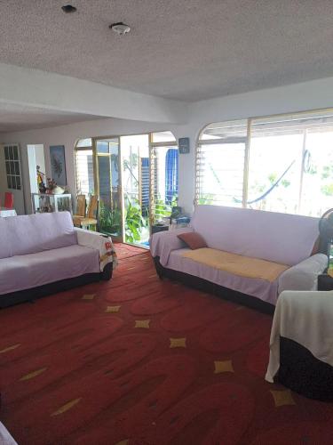 a living room with two couches and large windows at Casa Vacacional Chula Vista in Acapulco