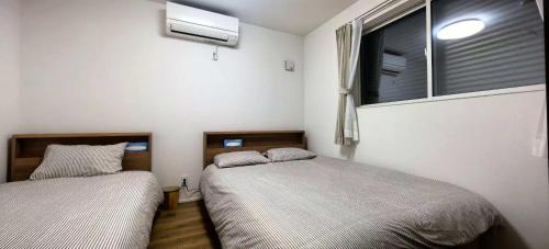 een slaapkamer met 2 bedden en een raam met een ventilator bij KamakurakoshigoeekimaeA in Kamakura