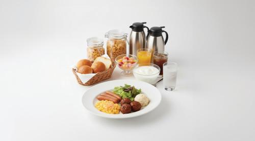 una mesa blanca con un plato de comida y bebida en Hop Inn Kyoto Shijo Omiya, en Kioto