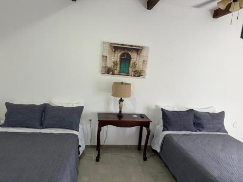 Hotel Carretas 2 في جالبان: غرفة نوم بها سريرين وطاولة مع مصباح