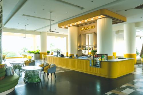 a lobby with a yellow counter and chairs and tables at Garden Sea View Resort in North Pattaya