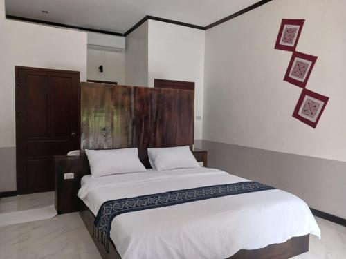 a bedroom with a large bed with a wooden headboard at Le Charme Pakbeng Villa in Pakbeng