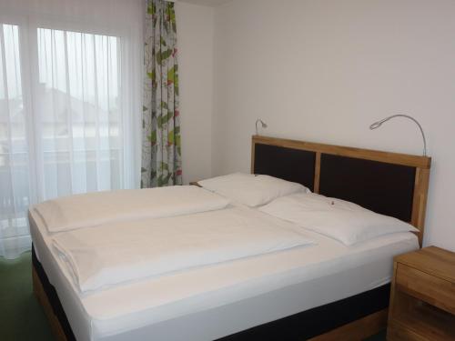 sypialnia z łóżkiem z białą pościelą i oknem w obiekcie Gasthof zur Post w mieście Schörfling