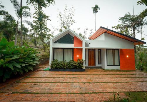 a small house with an orange and white facade at wayanadjunglevillas in Kenichira
