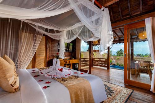 a bedroom with a large bed with a canopy at Kamania Villa Ubud by Dhananjaya Hospitality in Tampaksiring