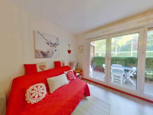 Schlafzimmer mit einem roten Bett und einem großen Fenster in der Unterkunft Appartement charmant au cœur de Les Rousses - FR-1-834-15 in Les Rousses