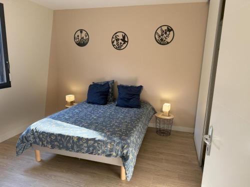 een slaapkamer met een bed met blauwe kussens en klokken aan de muur bij Gîte paisible dans la campagne de Bressolles, animaux admis - FR-1-489-596 in Bressolles