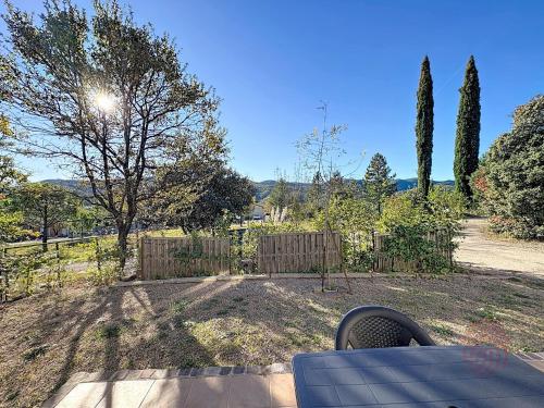 une cour arrière avec une clôture, des arbres et une table dans l'établissement Maison climatisée avec parking à Lamalou-les-Bains - FR-1-451-222, à Lamalou-les-Bains