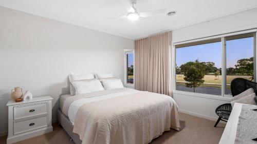 a white bedroom with a bed and a window at Regal Retreat in Saint Leonards