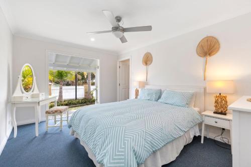 a white bedroom with a bed and a window at Seascape Cottage - Shelly Beach in Shelly Beach