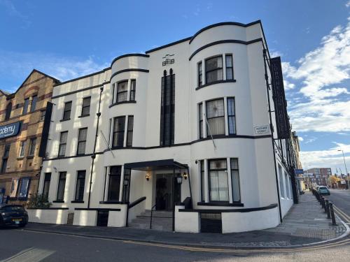 a white building on the corner of a street at Lord Nelson Hotel-Lime Street Station Liverpool by Compass Hospitality in Liverpool