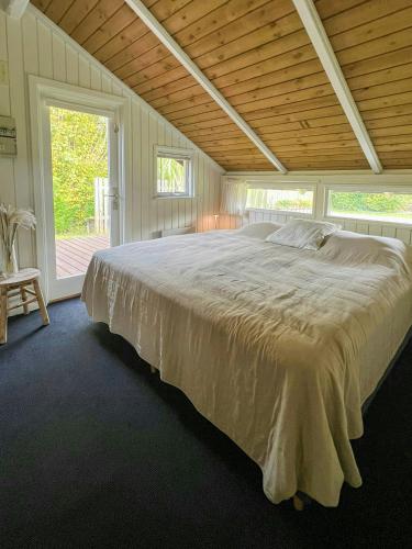 a large bed in a bedroom with a wooden ceiling at Kalmar House On Fejø Near The Beach in Vesterby