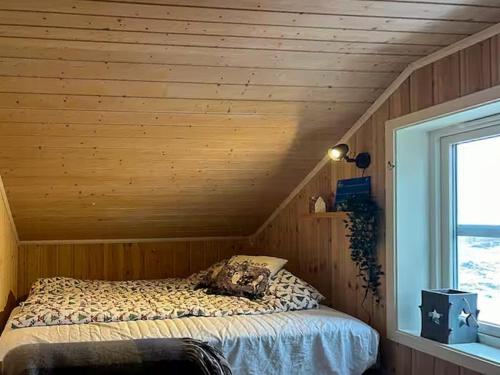Ce lit se trouve dans une chambre en bois dotée d'une fenêtre. dans l'établissement Mountain Cabin With Views Of Snasahøgarna, à Rundhögen