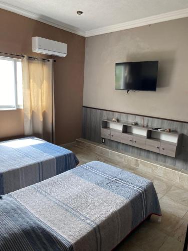 a bedroom with two beds and a television on the wall at Casa Mía Morelos in Chiconcuac