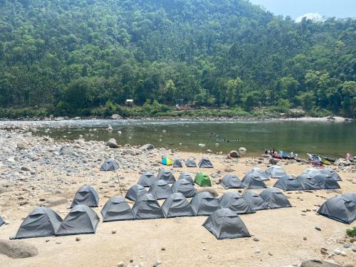 Un grupo de sombrillas en una playa junto a un río. en Rivers EdegesRetreat campsite, en Dawki