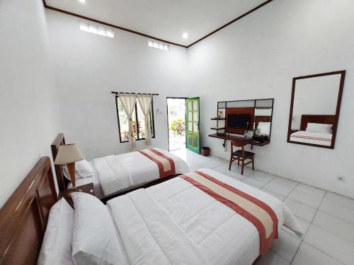 a bedroom with two beds and a desk and a mirror at Omah Kebon Guest House in Temanggung