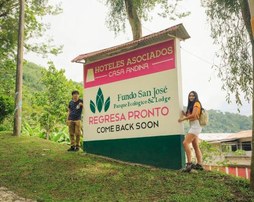 two people standing next to a sign in the grass at Fundo San Jose Parque Ecológico & Lodge Hotel Asociado Casa Andina in La Merced