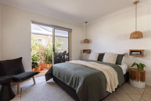 ein Schlafzimmer mit einem Bett, einem Stuhl und einem Fenster in der Unterkunft Carmine in Byron Bay