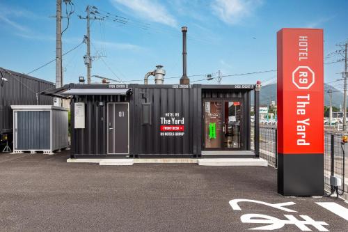 ein kleines schwarzes Gebäude mit einem Schild davor in der Unterkunft HOTEL R9 The Yard Tagawakawara 