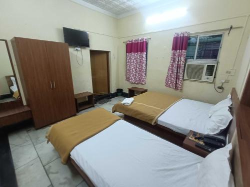 a hotel room with two beds and a television at Hotel O Down Town Hotel in Calcutta Bara Bazar