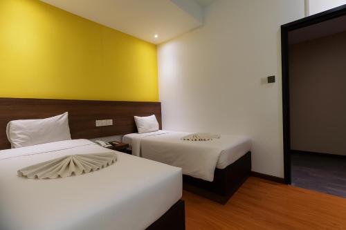a room with two beds and a yellow wall at Lemonade Hotel in Gua Sai