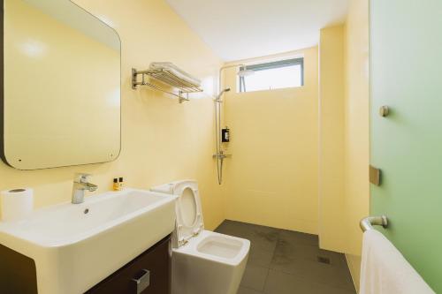 a bathroom with a sink and a toilet and a mirror at Lemonade Hotel in Gua Sai