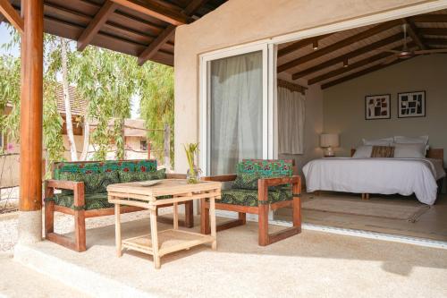 un patio con una mesa y sillas y una cama en Ecolodge Pout Pout, en Fatick