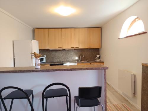 a kitchen with a counter and some black chairs at Maisonnette proche de Strasbourg in Vendenheim