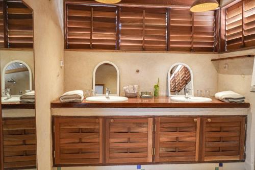 un baño con dos lavabos y dos espejos en Ecolodge Pout Pout, en Fatick