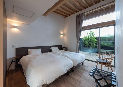 a bedroom with a large bed and a large window at 風の宿り in Isahaya